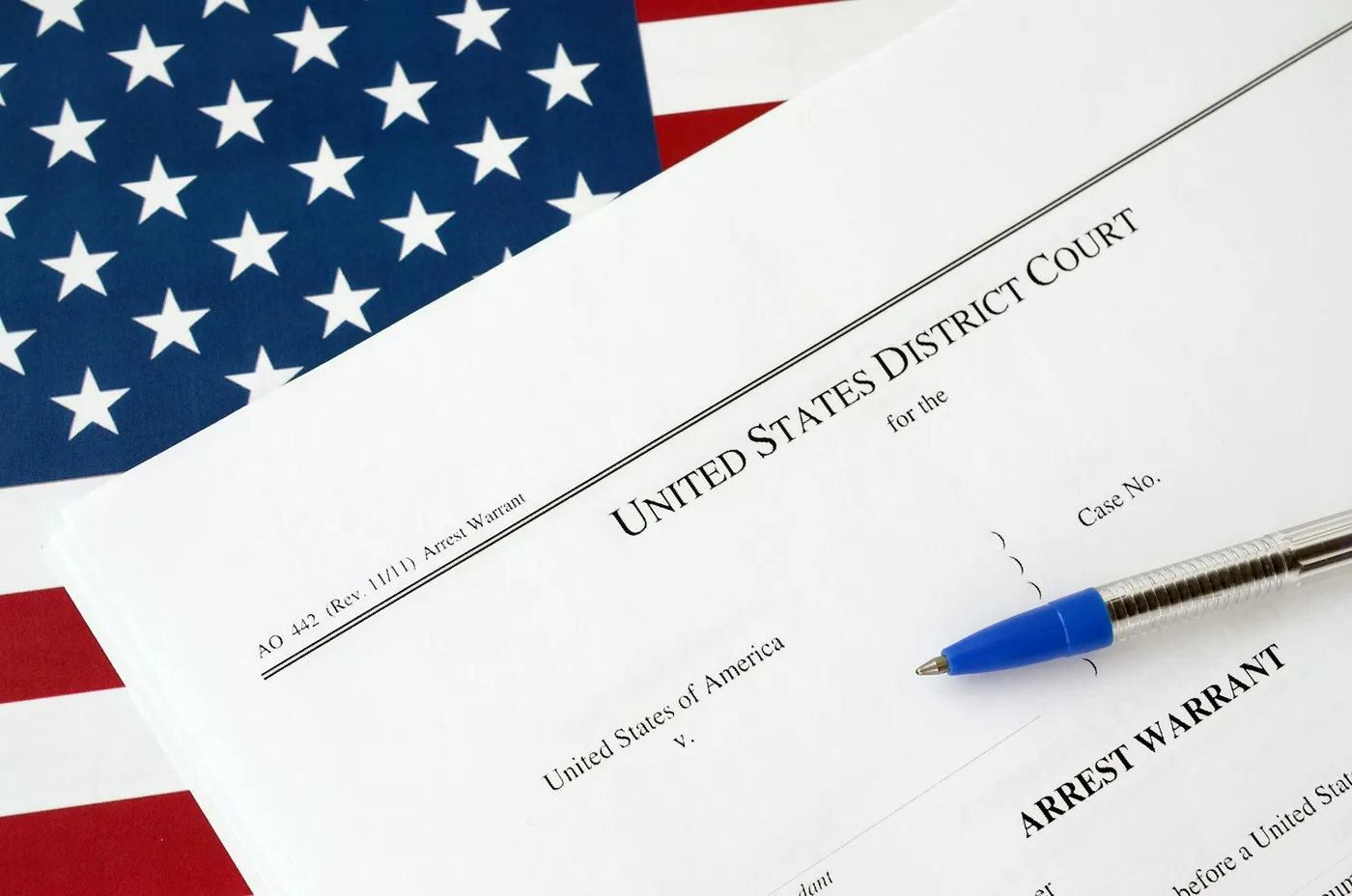 District Court Arrest Warrant court papers and blue pen on United States flag